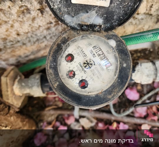 מונה מים עם מכסה פתוח וצינור ירוק
